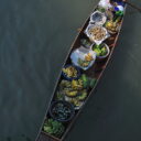 Local vendor selling fresh produce on a rowing boat at Tha Kha floating market