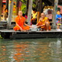 Buddhist monks feeding the fish in one of Bangkok canals