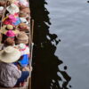 A vendor selling hats from a boat at Damnoen Saduak floating market