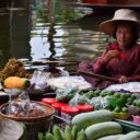 A boat with cooking supplies is passing by another one selling local snacks at Damnoen Saduak floating market