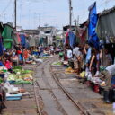 Shades are folded to make way for the train at the Railway Market. See the train passing on our private railway market tour from Bangkok.