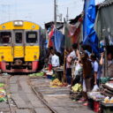 A train passing through a bustling Railway market. See it on our private railway market tour from Bangkok.